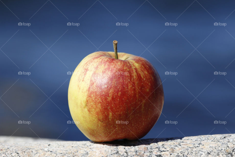 Red yellow apple on the rocks by the sea 