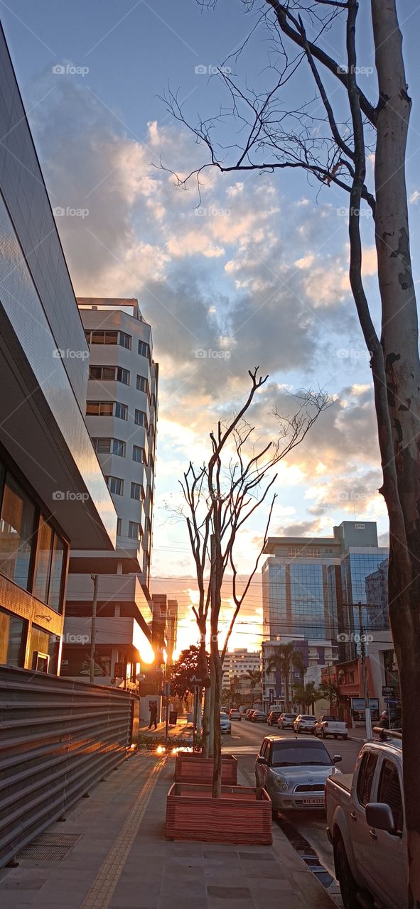 Streets, cars and buildings in the city at sunset