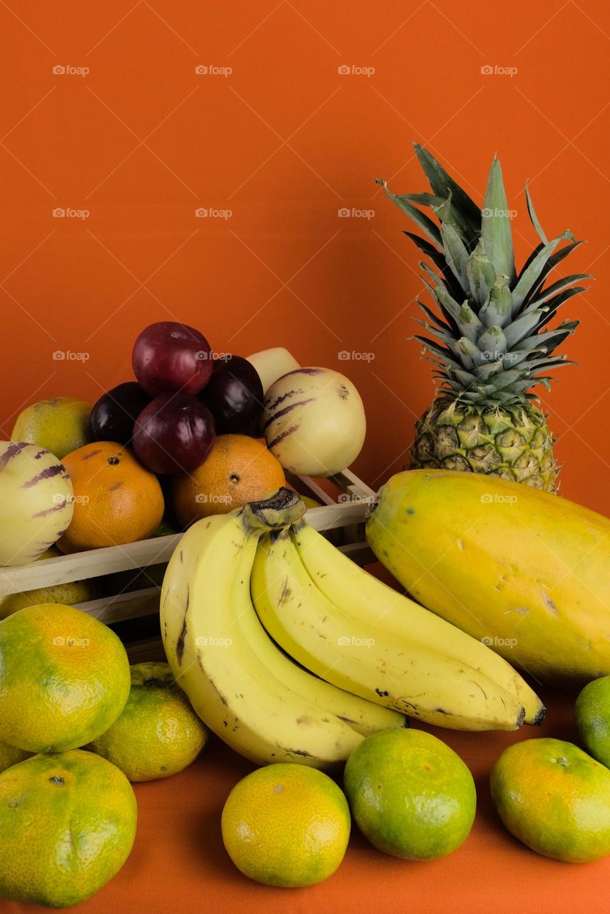 Tropical fruits for natural juice preparation on orange background