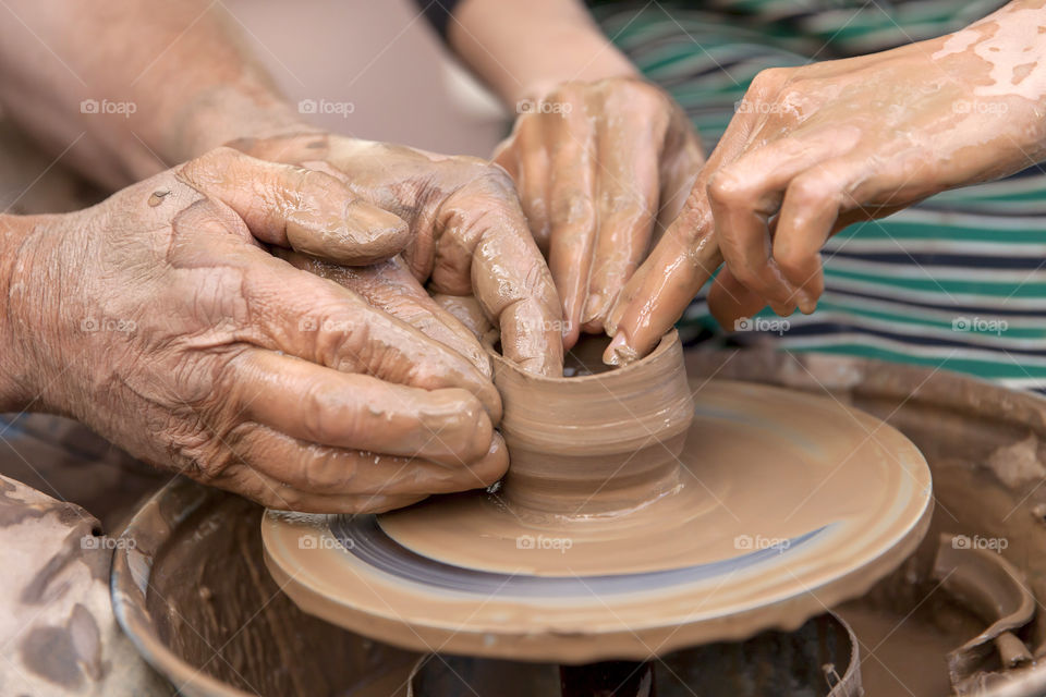 Hands working with clay on potter's wheel