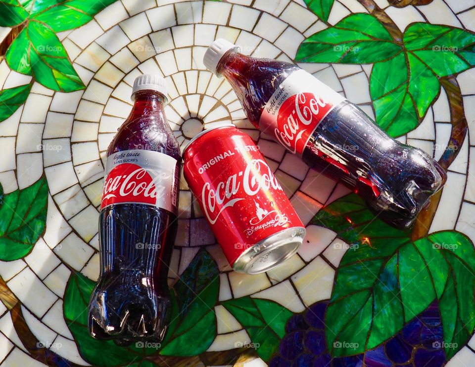 Two Diet Coke bottles and a can of Coca Cola on a garden table.