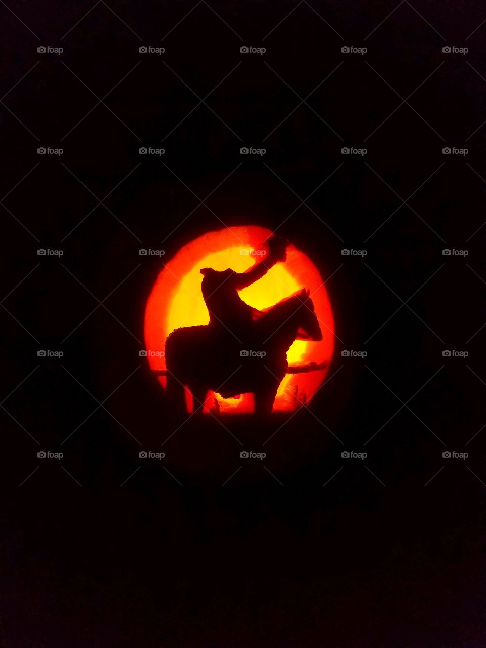 a glowing jack-o-lantern with a headless horseman carved into it