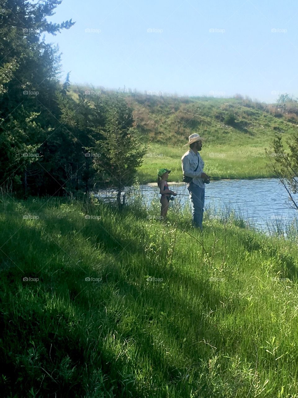 Father and daughter fishing at a fishing hole