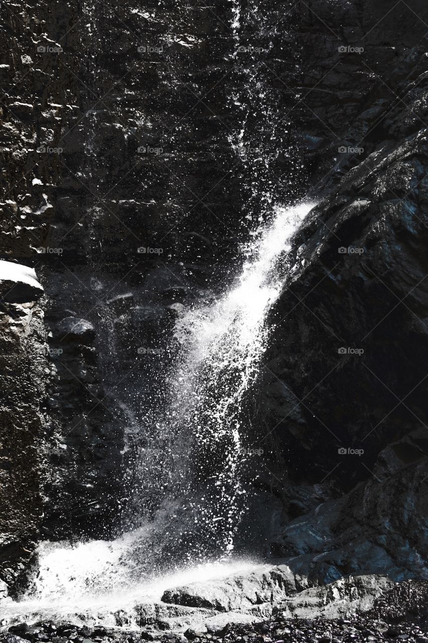 splashes and drops of water falling on the rock of a mountain spring, shot in black and white