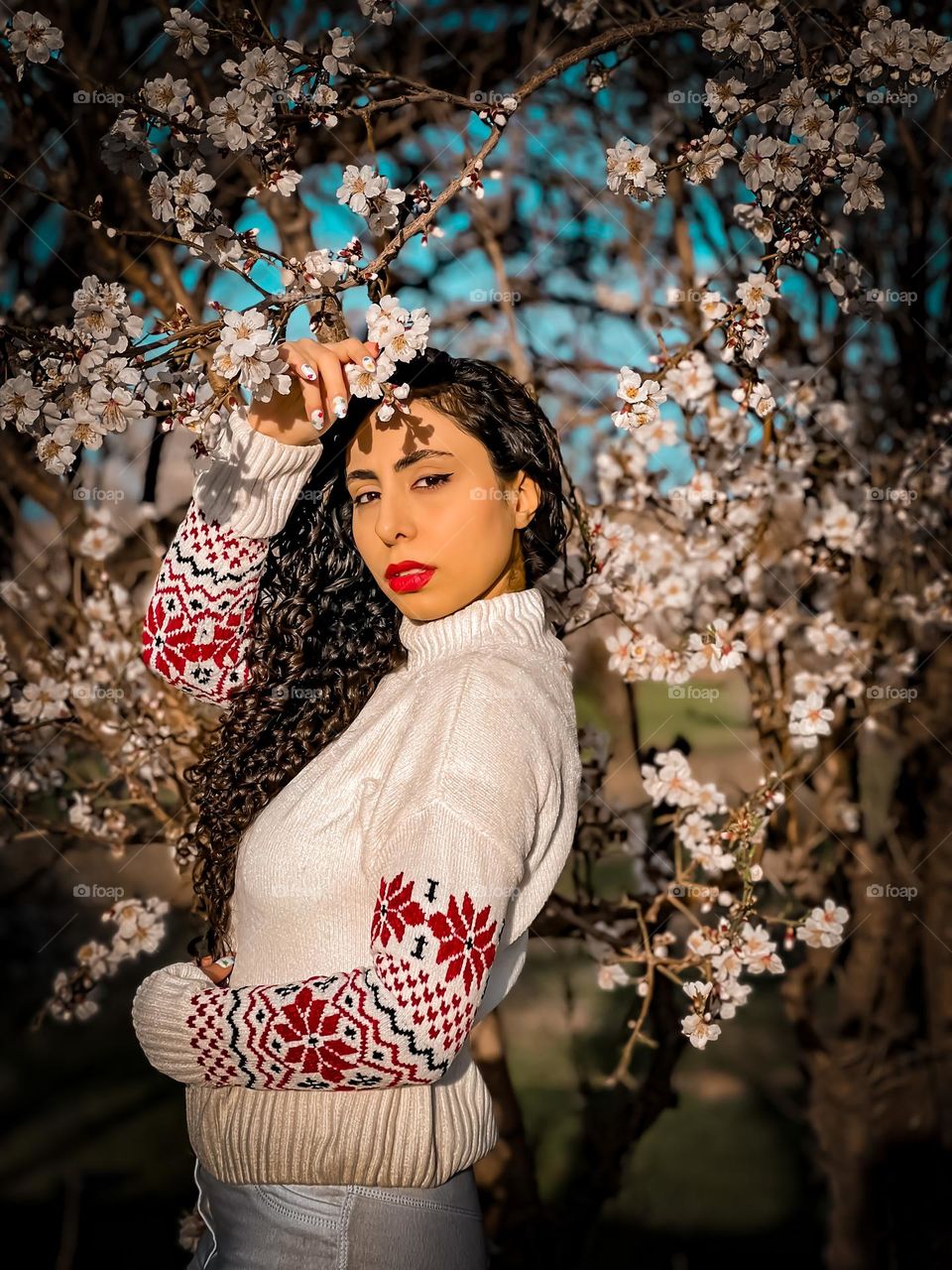 Curly-haired girl and blossoms in the spring air