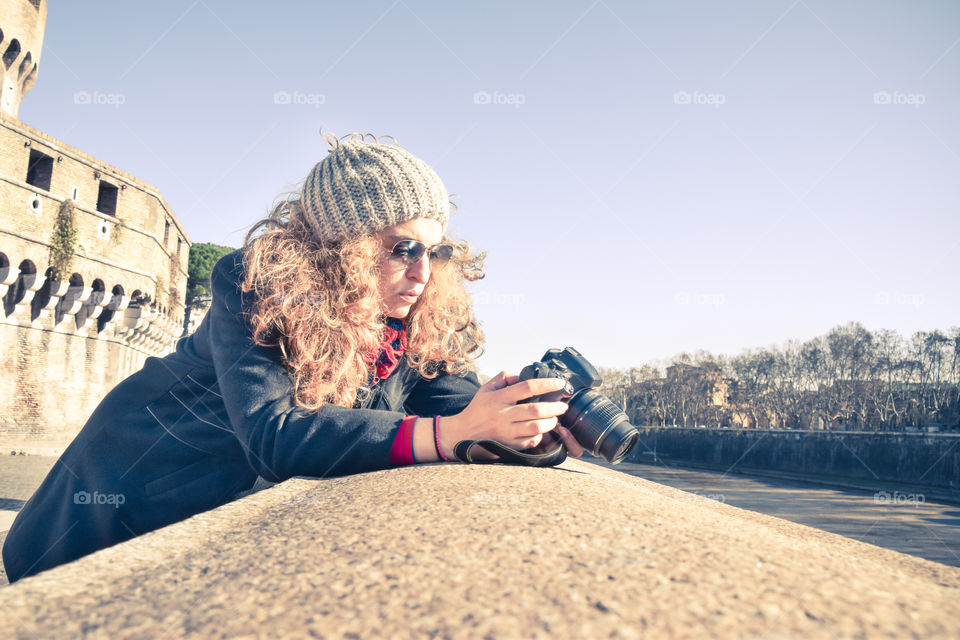 Beautiful Blonde Woman Photographer Wearing Sunglasses And Cap Using Her Camera In Winter
