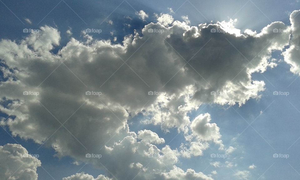 Sun's rays escaping around these puffy clouds