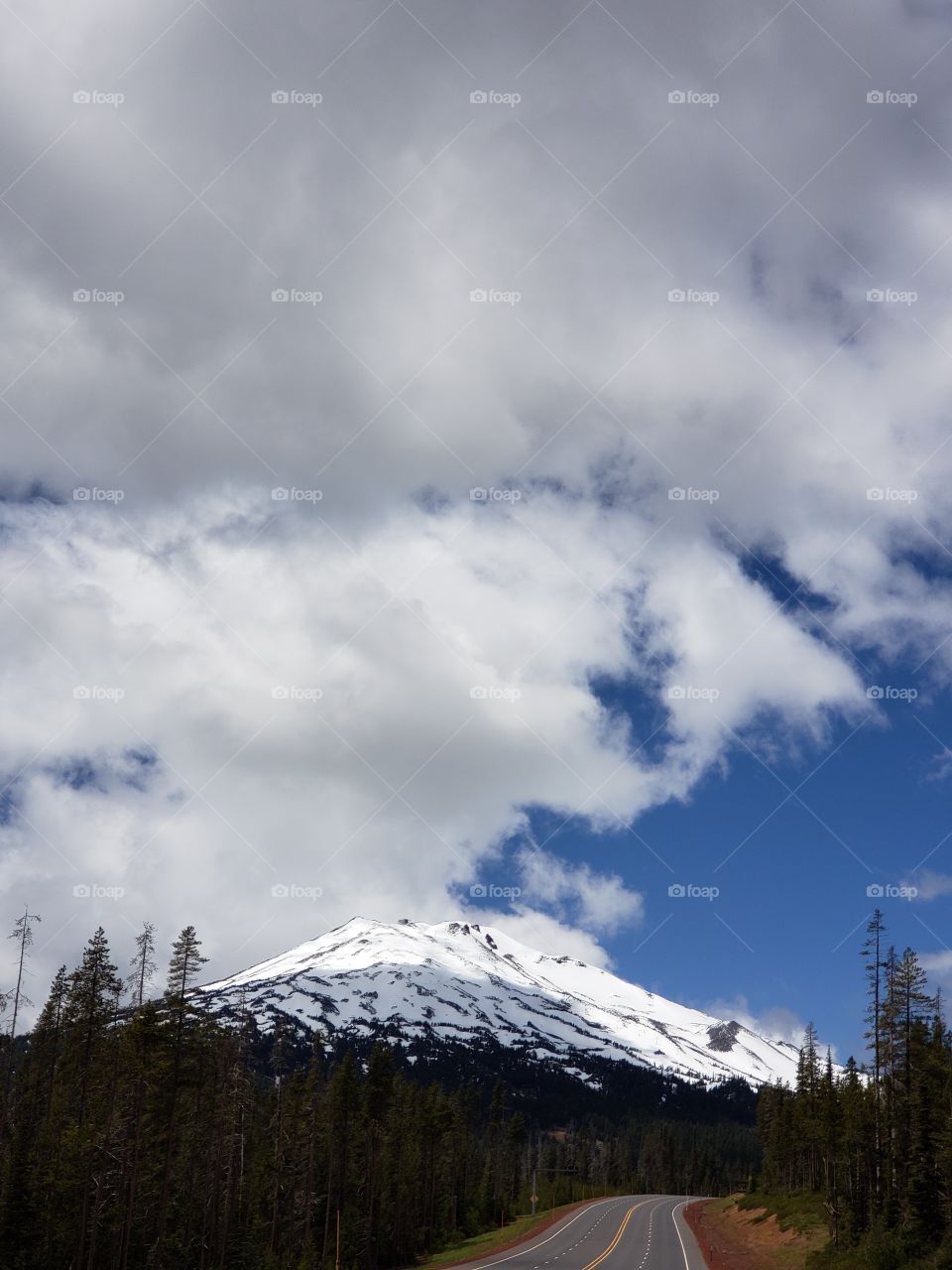 The sun breaks through the clouds on a summer day and illuminates Mt. Bachelor in Oregon's Cascade Mountain Range.