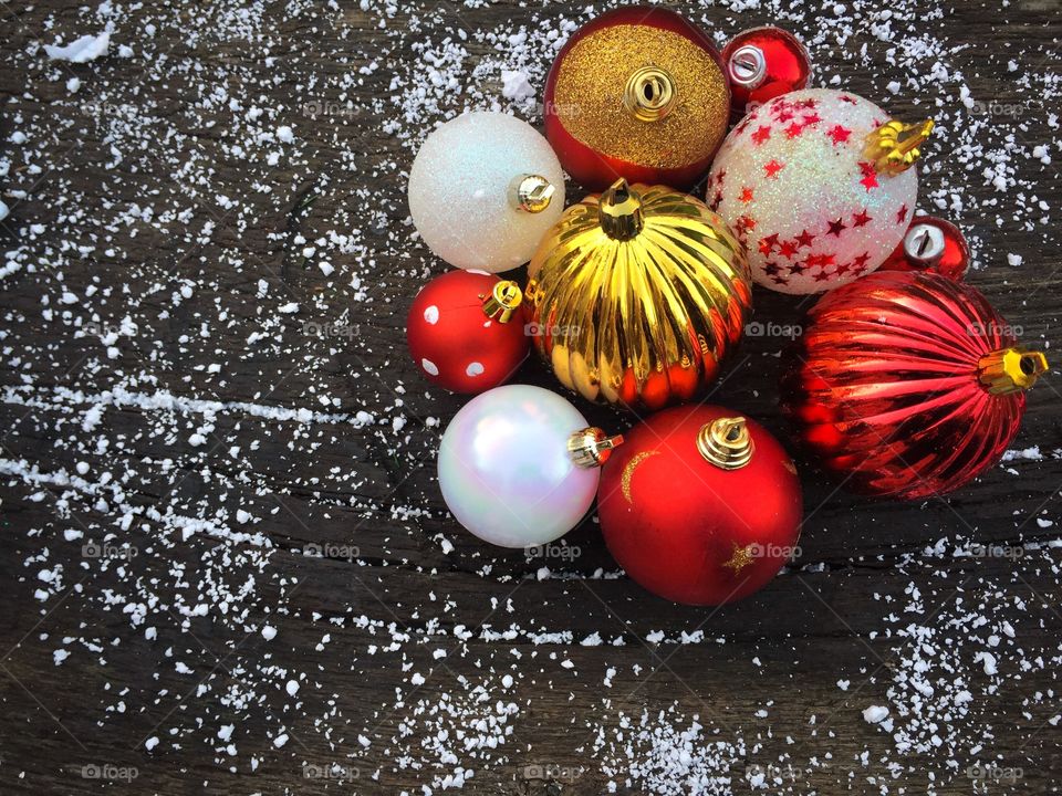 Red and white glittering Christmas globes on rustic wooden table powdered with snow