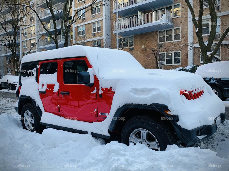 Red jeep covered by snow