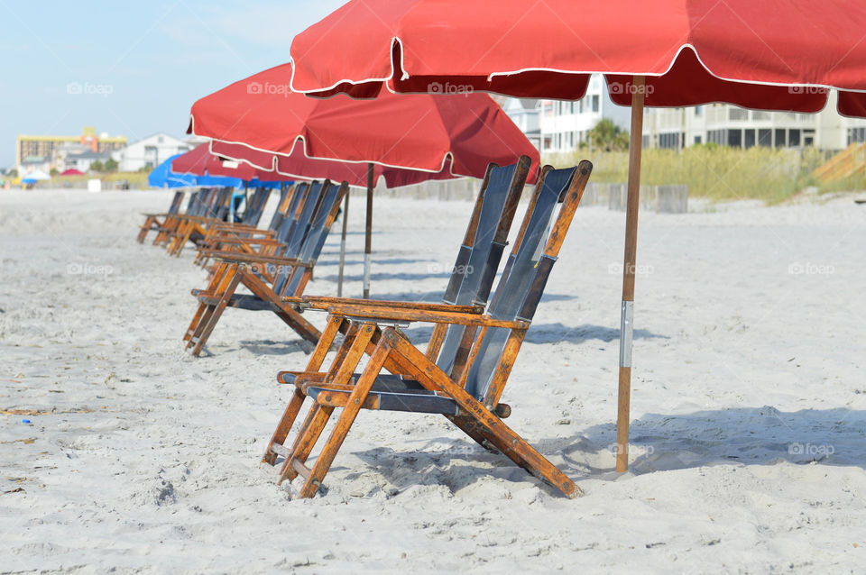 Row of empty lounge chairs and umbrellas set up on the shore of the beach