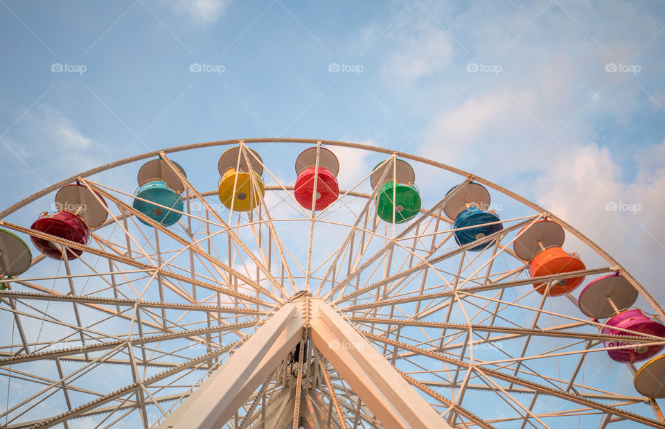 Amusement park ferris wheel. Blue sky with clouds in the background.