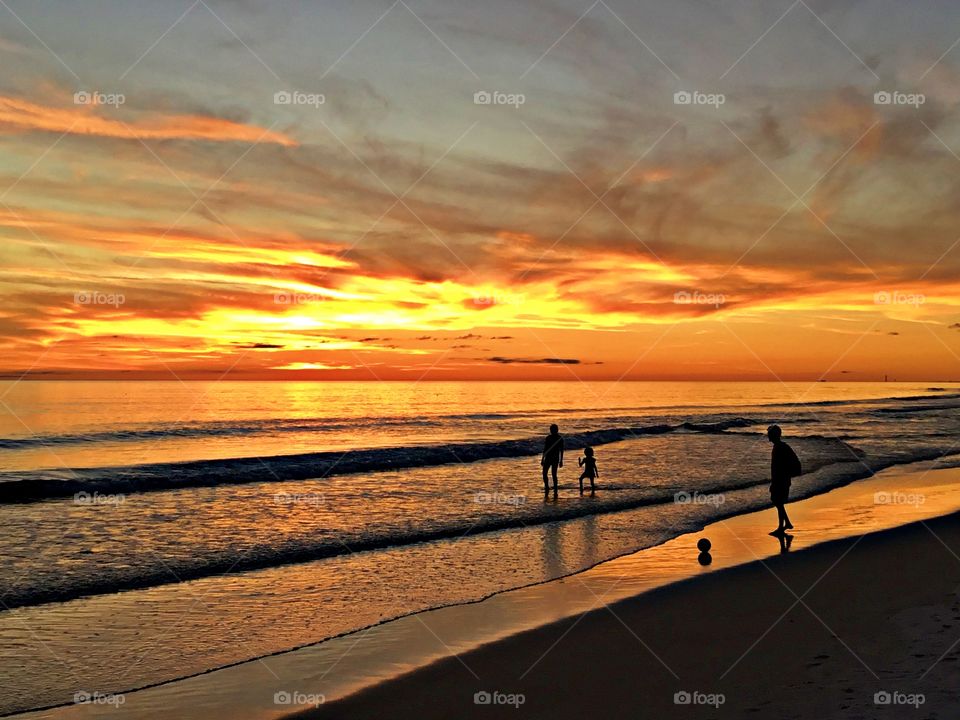 A family kicks the soccer ball around in the Gulf of Mexico during a colorful sunset - Sunrise and sunsets of our planet