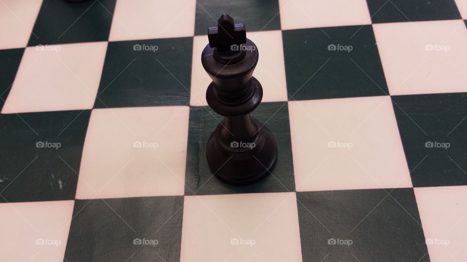 Black king chess piece on checkered game board