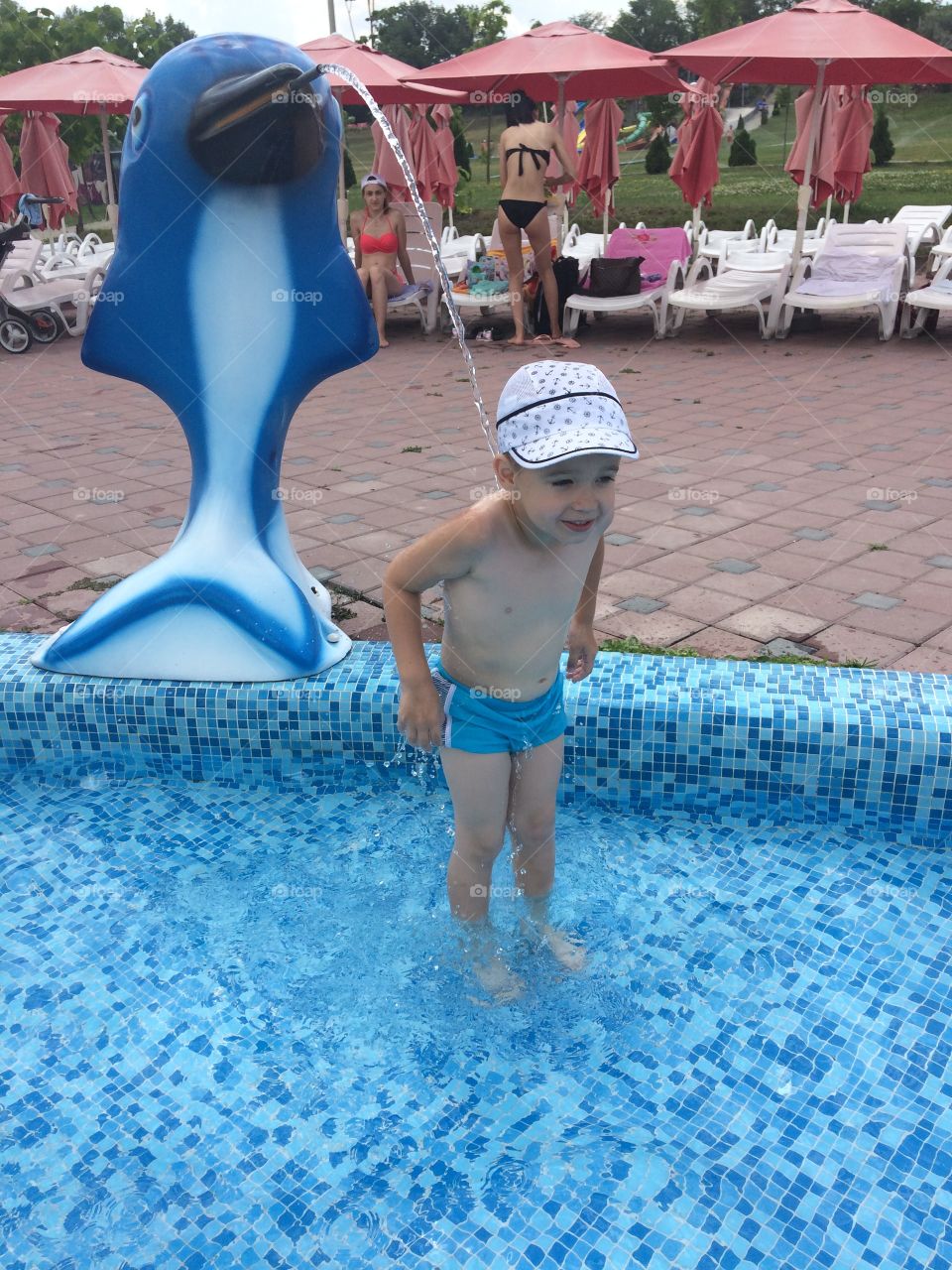 fountain in form of dolphin splashes on a boy