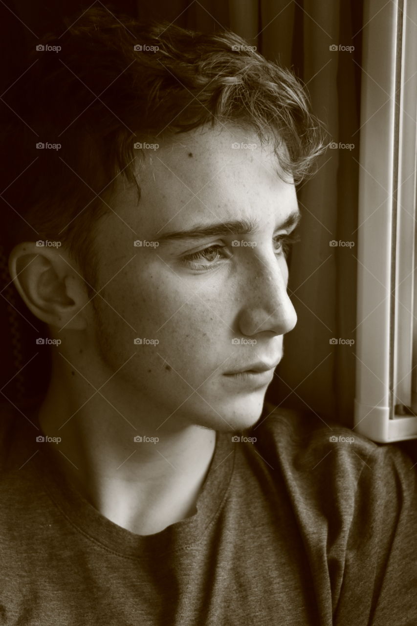 Portrait of teenage boy looking through the window