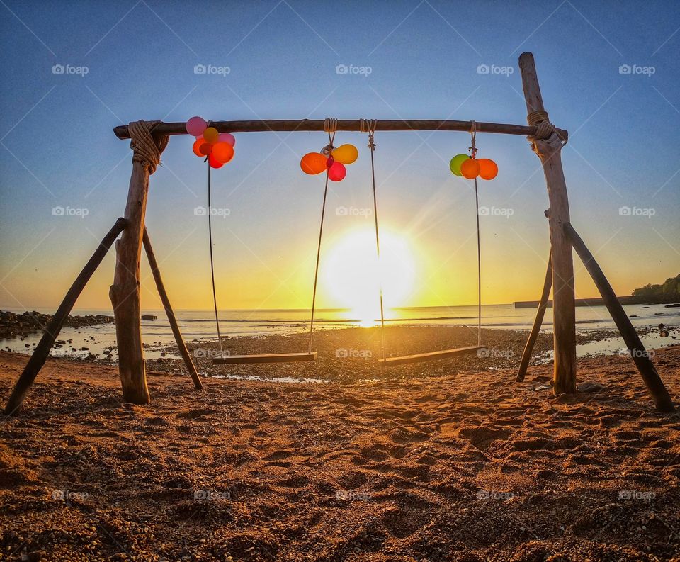 Beautiful scene of swing on beach in sunrise moment