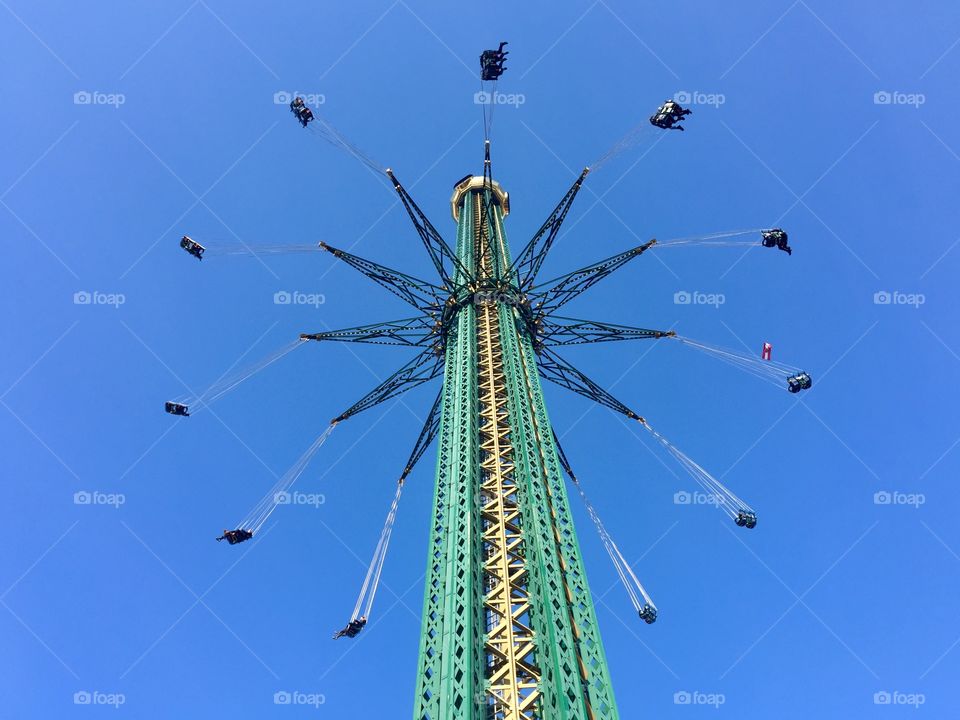 Swing ride in a very tall tower surrounded by blue sky in Prater, Wien