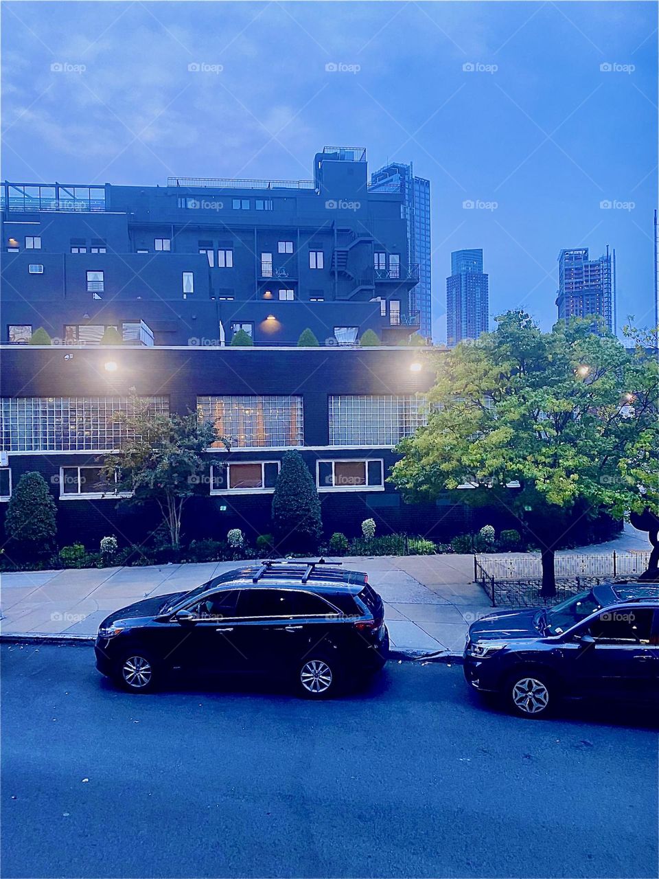This is the other side with a back entrance of the “BOX HOUSE HOTEL” opposite the “Pulaski Bridge” at “Newtown Creek”. The nighttime illumination is already on at twilight time. 2023. Hypnotic Productions
