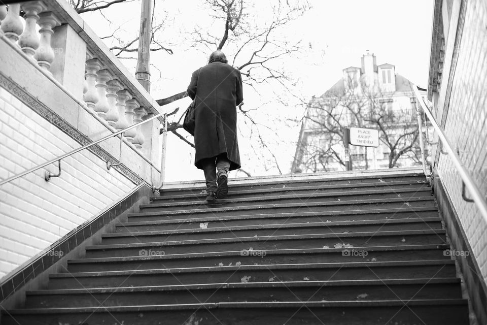 Lonely man in coat ascends stairs