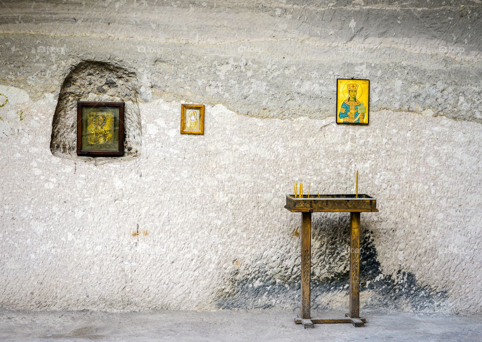 gray wall with icons, small table with church candles in the monastery