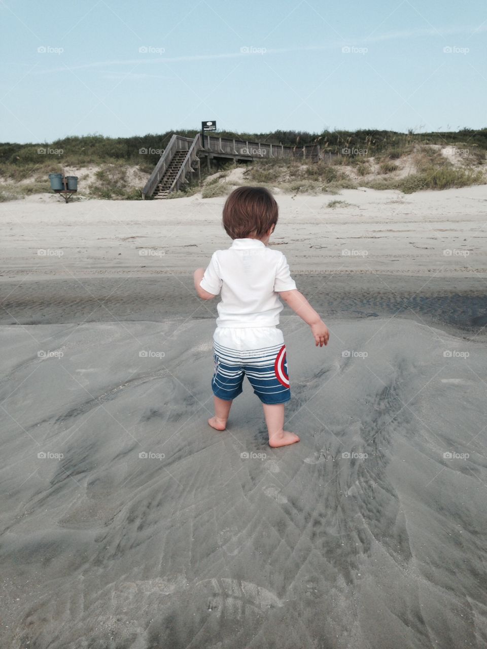 Toddler walking down the beach.