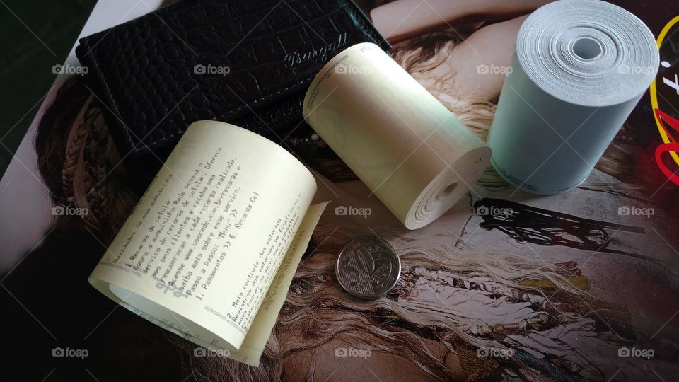 Carteira, bobinas, ticket de finanças e moeda.