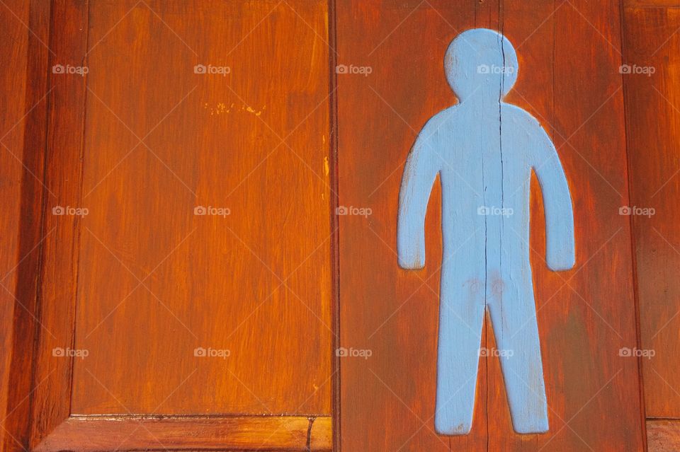 An orange wooden outside men's public restroom door at a shopping area in San Miguel de Allende, Mexico.