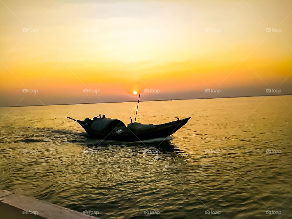 A boat sailed on the river at sunset time.I is a scenery that I had taken in my mobile camera, when I went to a tour to bay of Bengal at Sunderban , India .