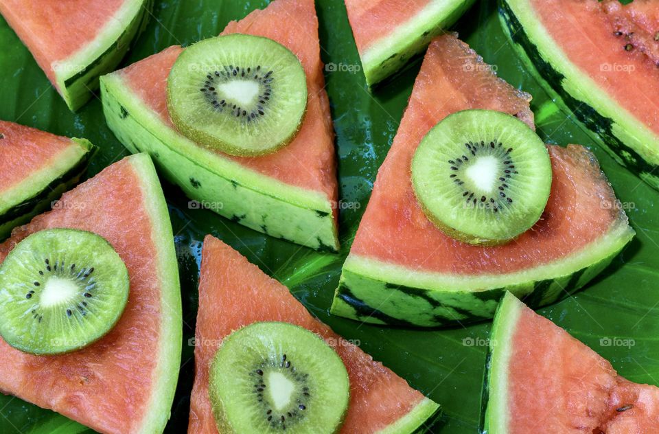 Slices on kiwi on slices of melon on a banana leaf