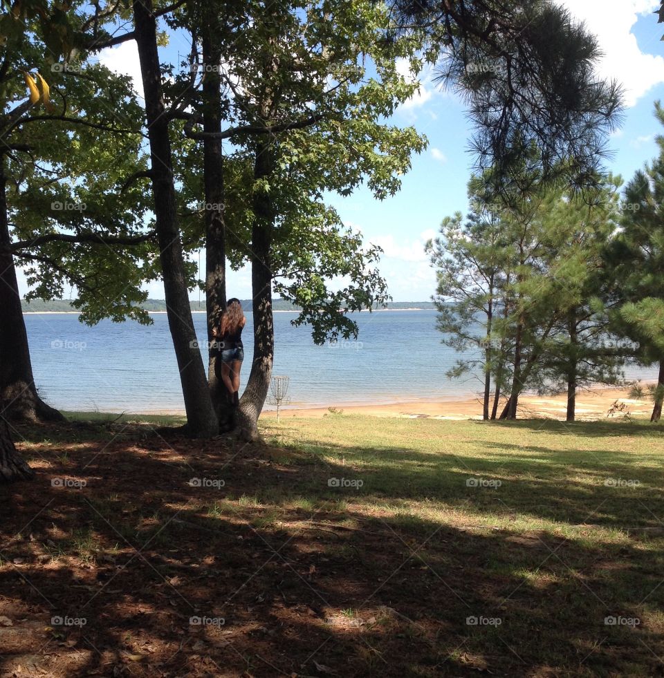 Girl in tree by lake daydreaming