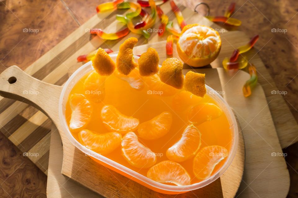 Delicious orange jelly with tangerine slices in a container and jelly worms.