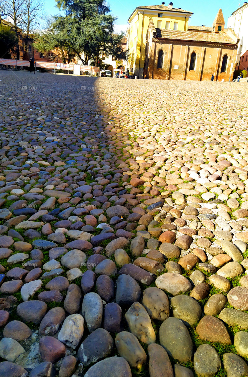 An area of ​​paving stones, which is divided by a sunbeam into two parts