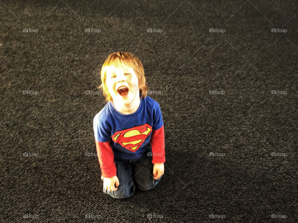 Young happy joyful boy in a Supman shirt, his superhero costume