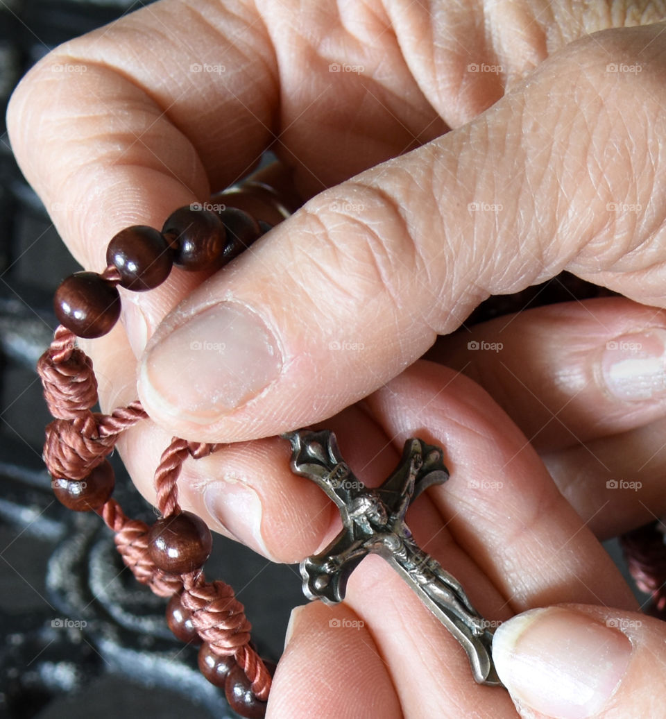 Woman’s hands holding a crucifix with rosary beads 