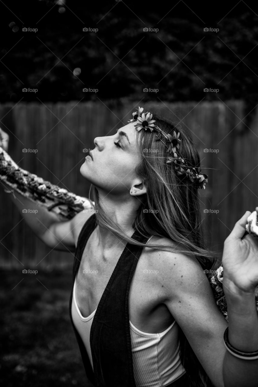 Vintage boho retro vibe portrait of a hippie millennial woman wearing a crown of flowers and feeling the wind outdoors 