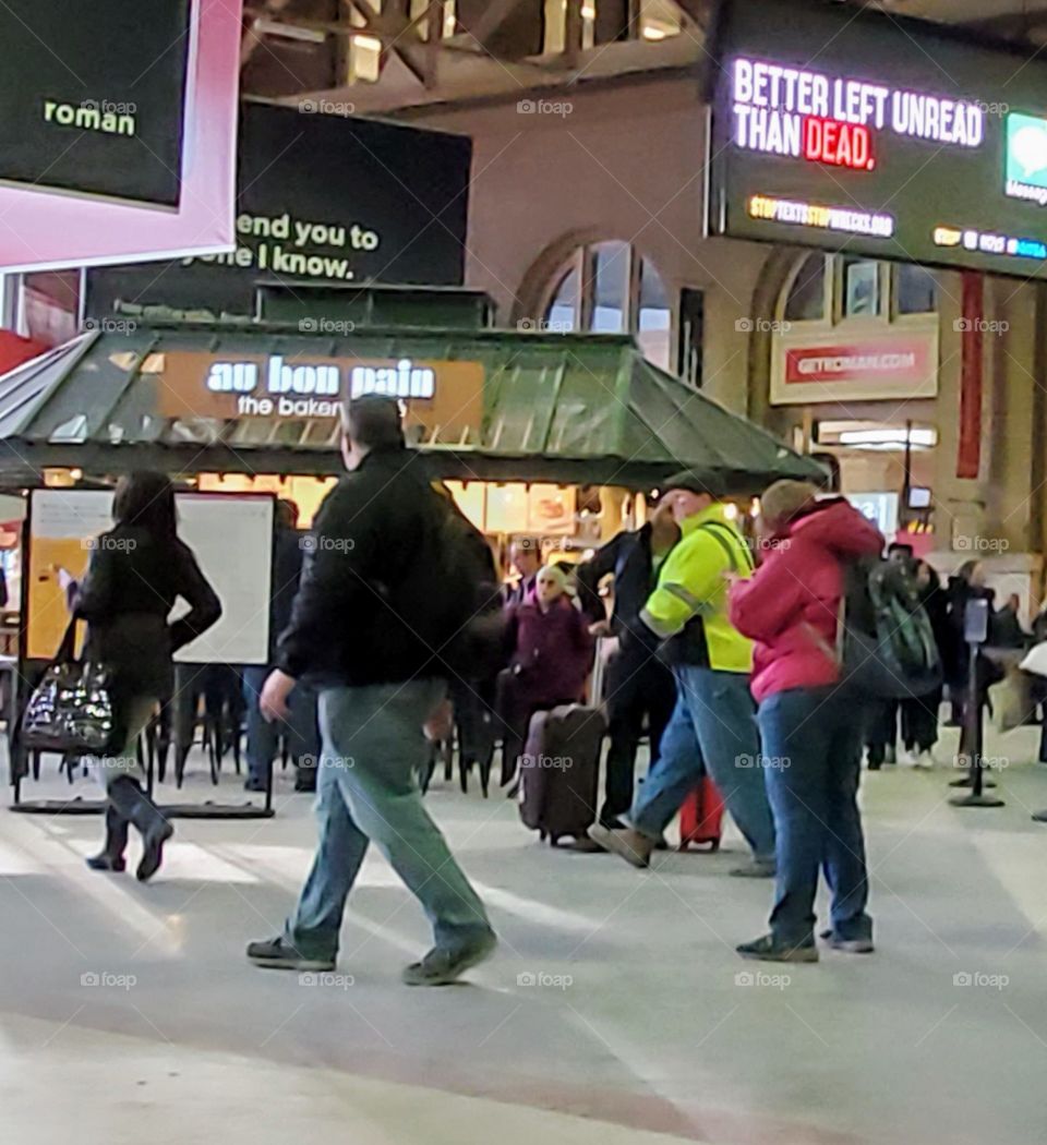 Train departure called, some people are heading to the platform. Some people are standing & others walking around. They are commuters leaving the city.