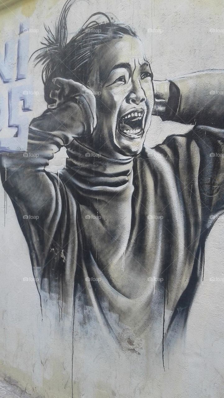Street art depicting a girl covering her ears and an expression of fear.