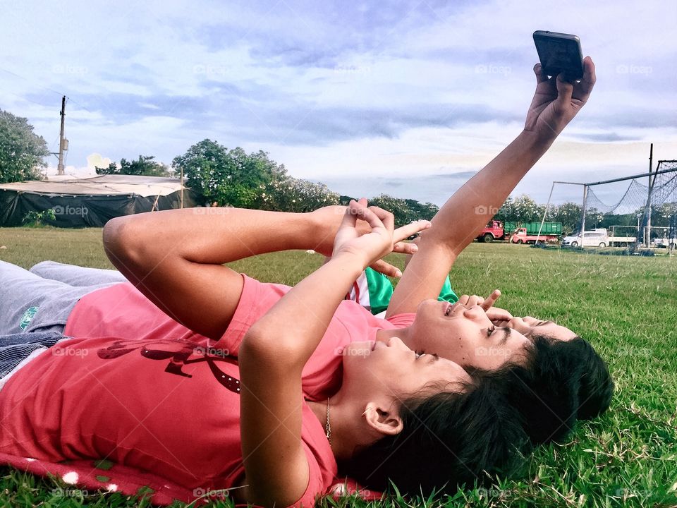 Mother and children lying in park taking selfie