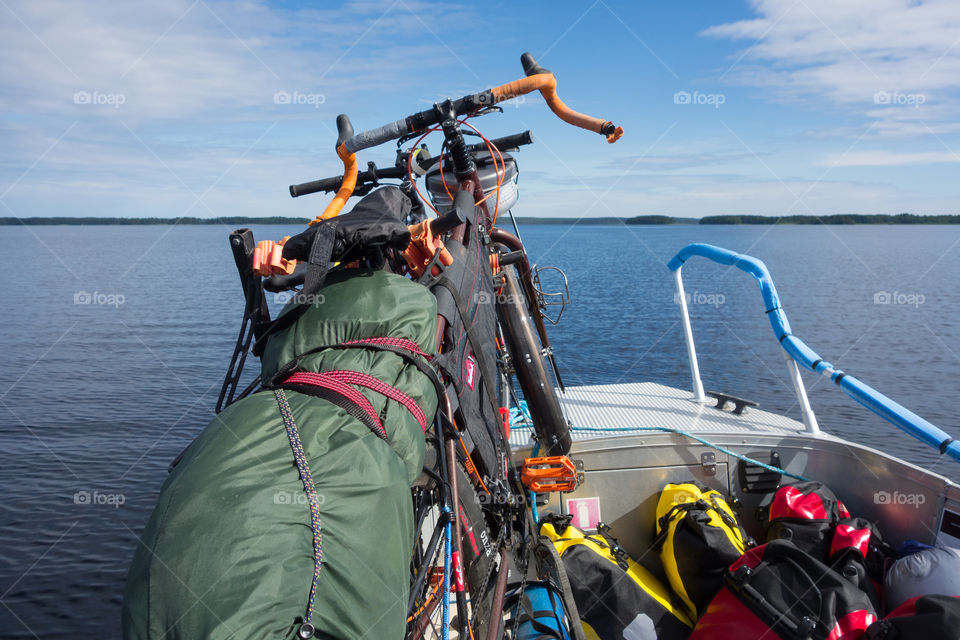 Taipalsaari, Finland – July 2, 2015: Two touring bikes tied securely to a fishing boat with colorful panniers on the boat floor by the lake Saimaa, Finland for crossing to the other side of the lake from Taipalsaari on 2 July 2015.