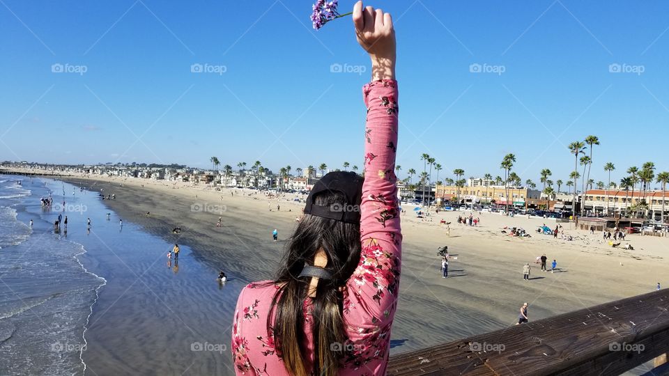 woman holding up a flower at the ocean