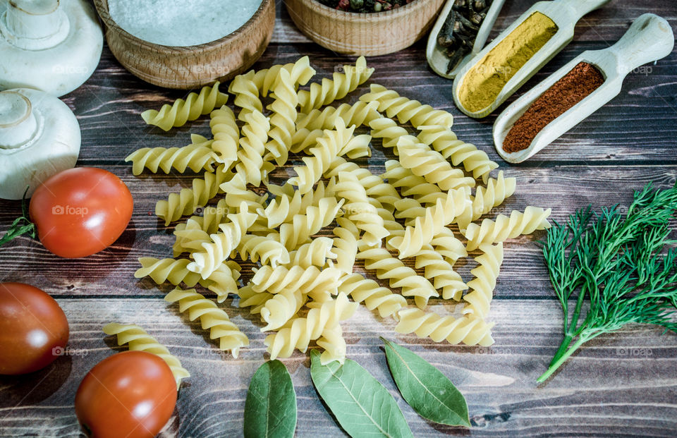 Raw pasta with ingredients and wooden accessories