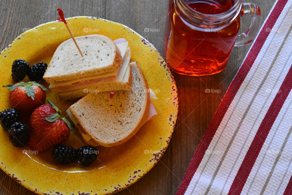 Ham and cheese sandwich with fruit and a glass of juice