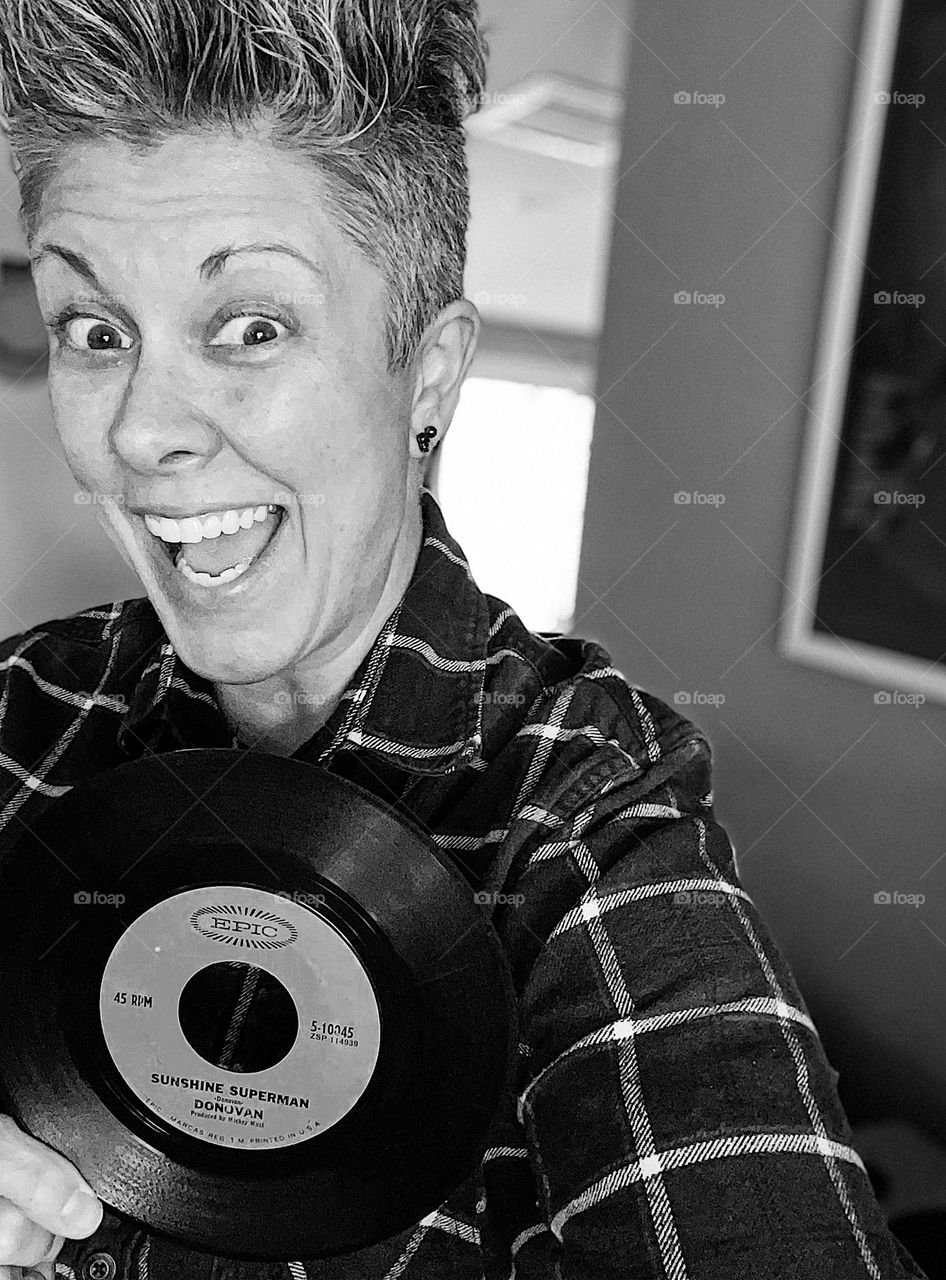 Woman poses with 45 record, tell me your age without telling me your age, black and white portrait, woman excited for birthday, playing around on your birthday
