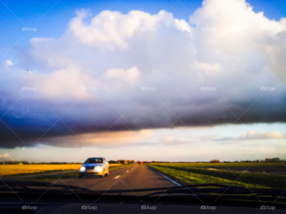 Car on a country road with cloudy sky