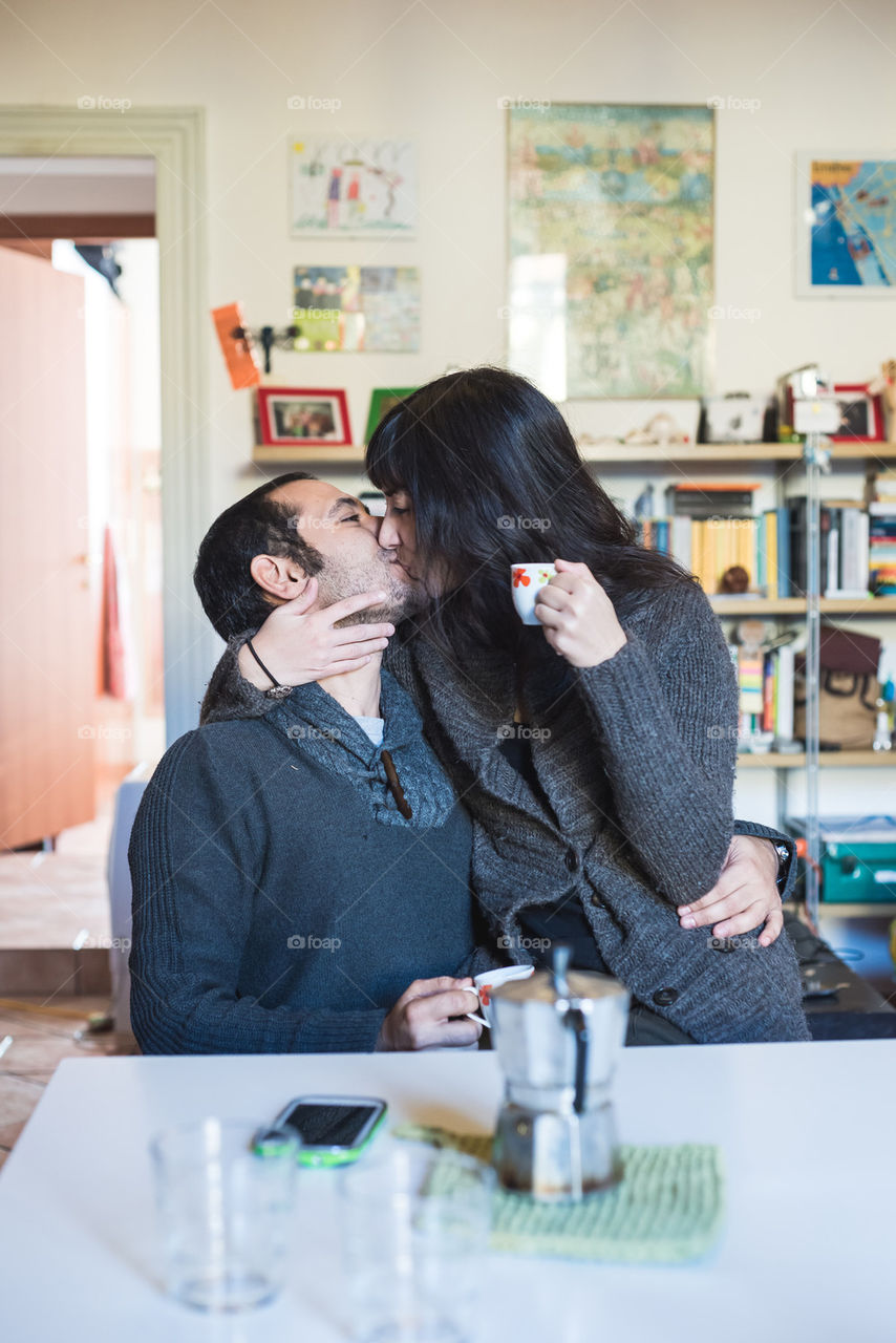 couple kissing at home during breakfast drinking coffee