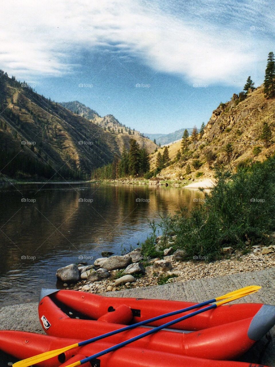 Red inflatable kayaks along the shore of a river in the  mountains of the Western United States