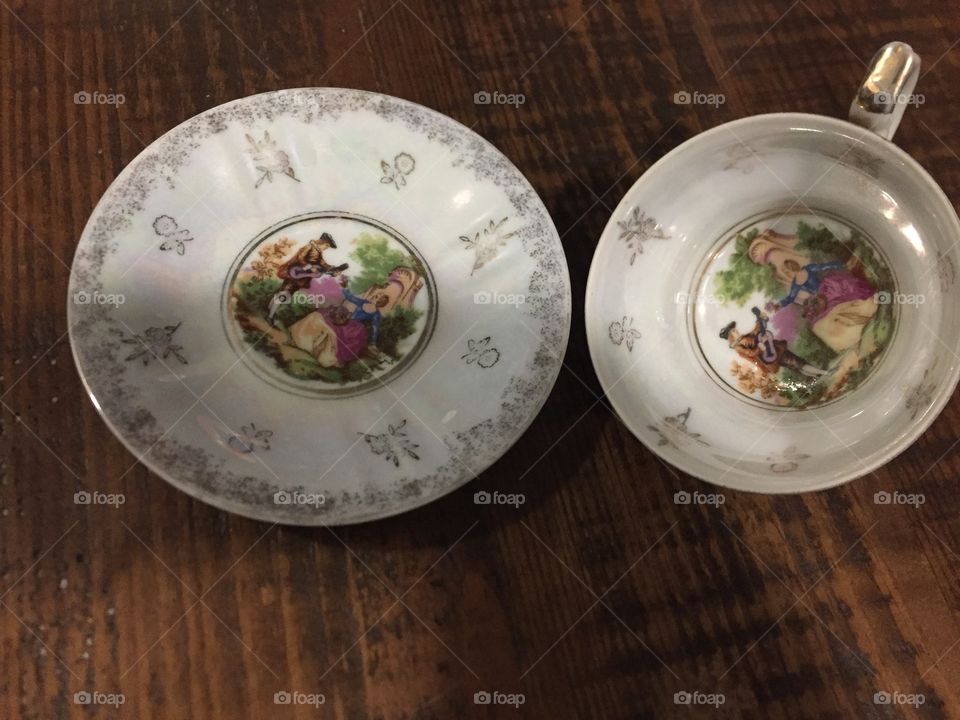 The little tea cup and saucer I’m a top view showing True art it’s a beautiful garden scene with a man and a woman