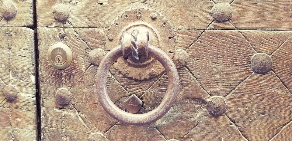 Antique door knocker on an old wooden door in the Tuscan town of Cortona, Italy