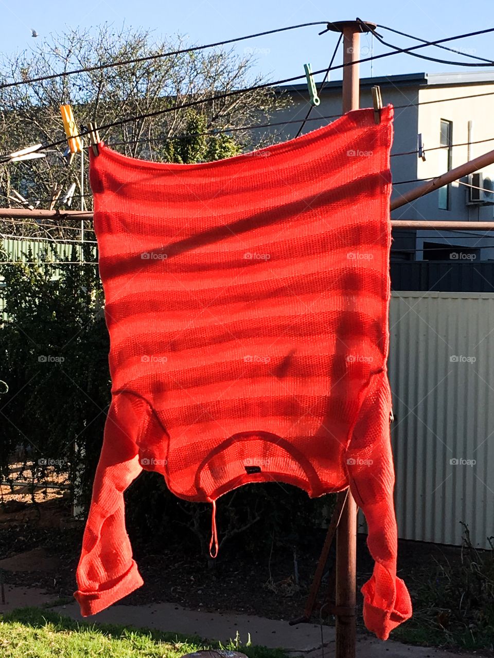 Coral red pink orange sweater jumper hanging in clothesline laundry hanging to dry 